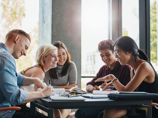 Fünf Personen rund um einen Tisch sitzend.