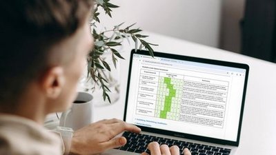 Eine Person von hinten vor einem aufgeklappten Laptop.