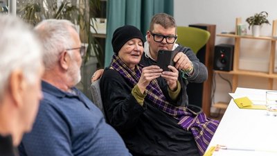 Aufnahme eines digital Überall Workshops. Drei Personen sind zu sehen wobei die einzige Frau am Bild ein Smartphone in der Hand hält.