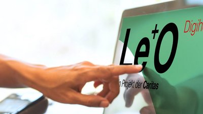 Zwei Hände auf Laptop-Tastatur, eine weitere Hand zeigt auf den Bildschirm des Geräts.