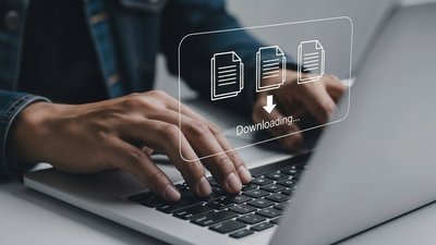 Zwei Hände auf einer Laptop Tastatur, darüber schwebt ein Download Icon.