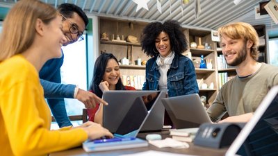 Fünf Menschen rund um einen Tisch, jeder mit Laptop vor sich.