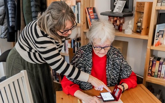 Eine Frau erklärt einer älteren Frau etwas auf dem Smartphone.