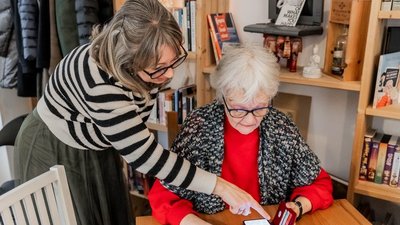 Eine Frau erklärt einer älteren Frau etwas auf dem Smartphone.