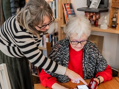 Eine Frau erklärt einer älteren Frau etwas auf dem Smartphone.