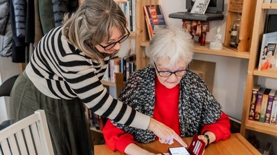Eine Frau erklärt einer älteren Frau etwas auf dem Smartphone.