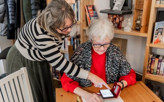 Eine Frau erklärt einer älteren Frau etwas auf dem Smartphone.