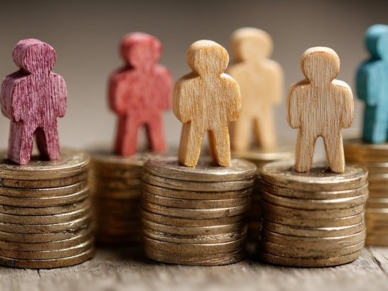 Sechs bunte Holzfiguren auf je einem Stapel Münzen.